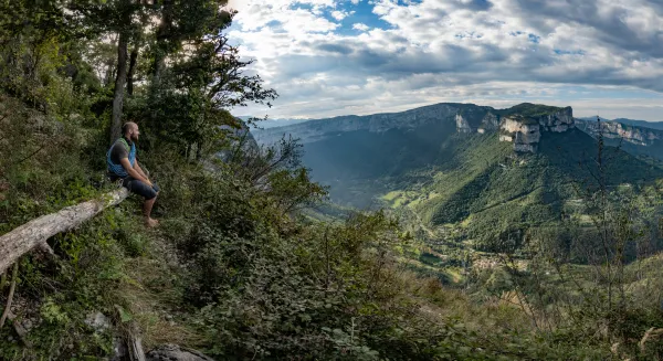 Personne assise sur un banc devant panorama du Vercors au dessus des falaises de Presles